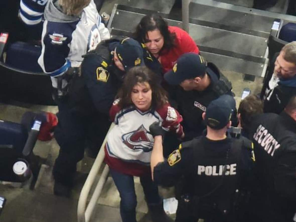 A Colorado Avalanche fan is removed by police after a fight at Tuesday night's Winnipeg Jets game. (@CBrooksie84/Twitter - image credit)