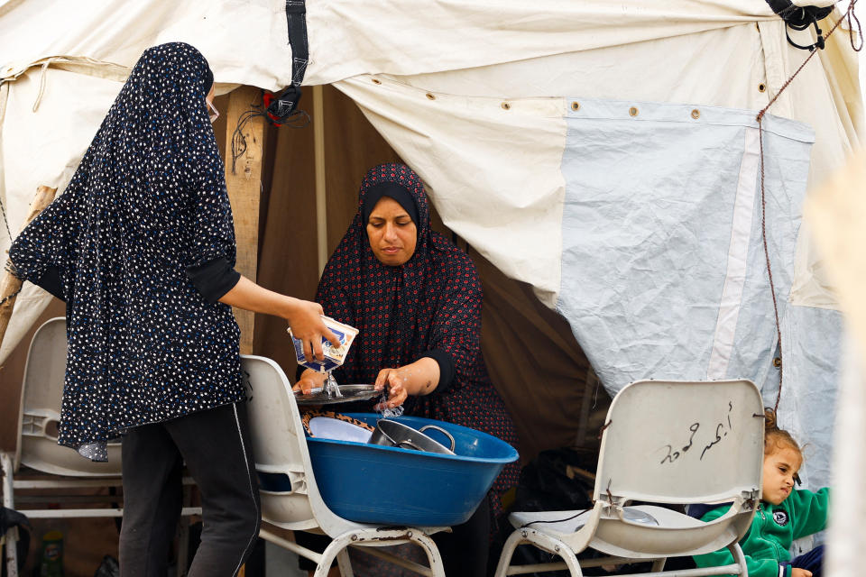 Displaced Palestinian women wash dishes, amid the ongoing conflict between Israel and Palestinian Islamist group Hamas, in a tent camp in Khan Younis in the southern Gaza Strip, November 20, 2023. REUTERS/Ibraheem Abu Mustafa