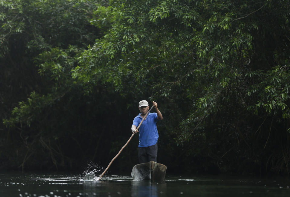 A man paddles along the Calobebora river near the community of El Terron, Panama, Friday, Jan. 17, 2020. A pregnant woman, five of her children and a neighbor where round up by about 10 lay preachers at the remote hamlet on Jan. 13 and tortured, beaten, burned and hacked with machetes to make them "repent their sins", authorities said. (AP Photo/Arnulfo Franco)