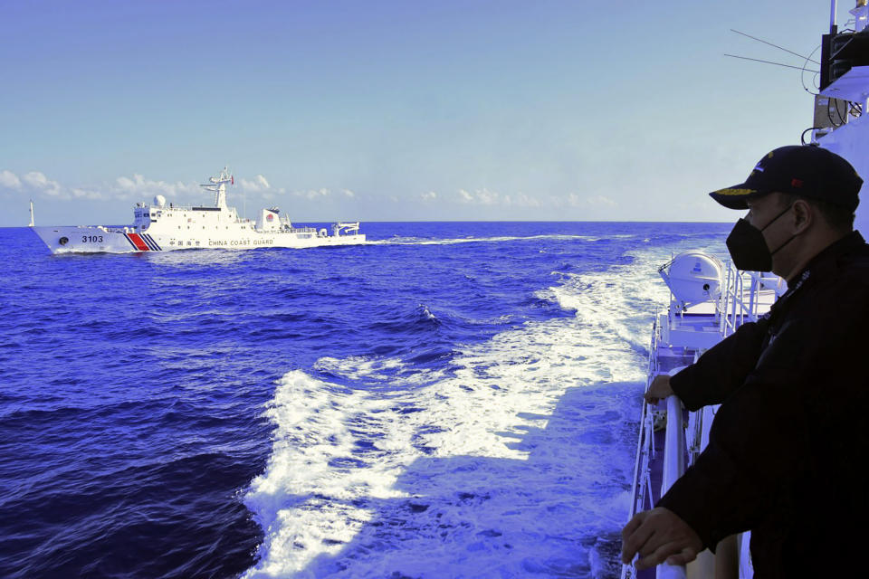 In this photo provided by the Philippine Coast Guard, a Philippine Coast Guard looks as a a Chinese Coast Guard ship sails near them during their patrol at Bajo de Masinloc, 124 nautical miles west of Zambales province northwestern Philippines on March 2, 2022. Chinese coast guard ships have maneuvered dangerously close to Philippine coast guard ships at least four times since last year near a disputed shoal that increased the risks of collision and violated international safety regulations, the Philippine coast guard said Sunday. (Philippine Coast Guard via AP)