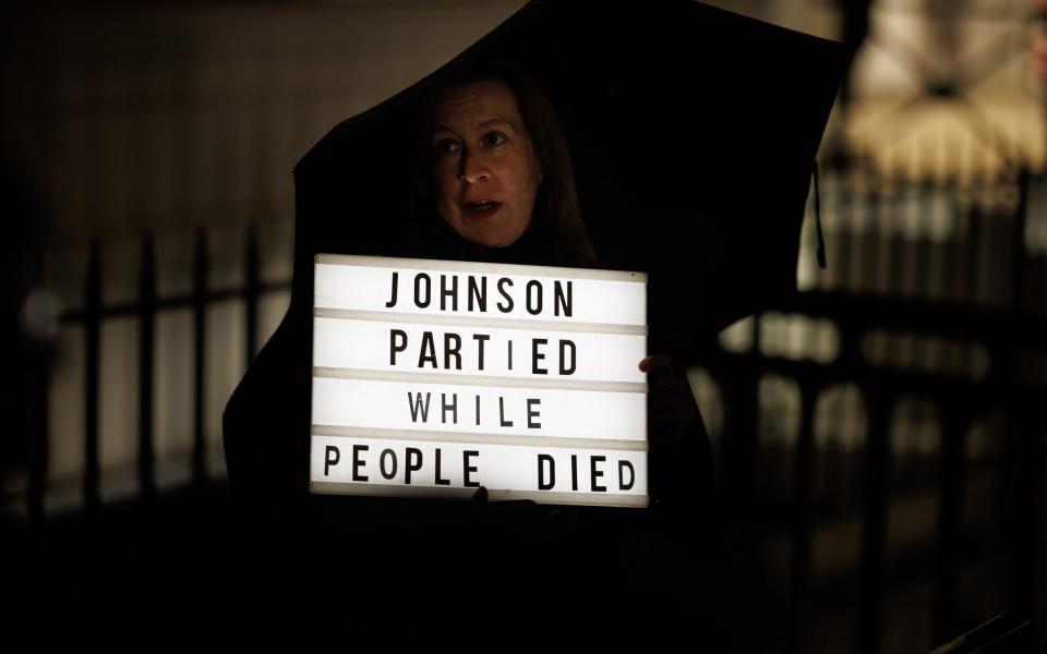 A woman protests ahead of the arrival of Former British Prime Minister Boris Johnson to the Covid Inquiry on December 7, 2023 in London, England. Britain's former Prime Minister will be questioned during phase 2 of the Covid-19 Inquiry over government decision-making during the pandemic.