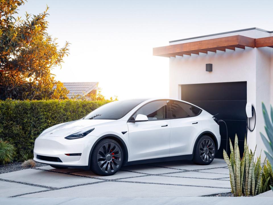 The Tesla Model Y electric SUV charging at a home.