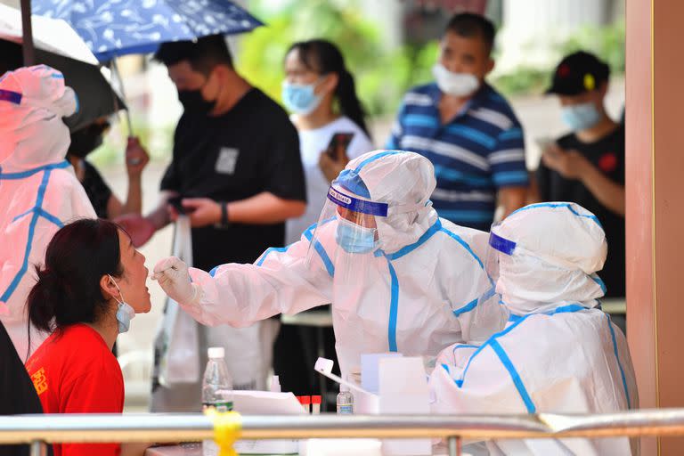 Trabajadores de la salud recolectan muestras de hisopado en un sitio de pruebas nucleicas de la COVID-19, en la comunidad de Nandaqiao