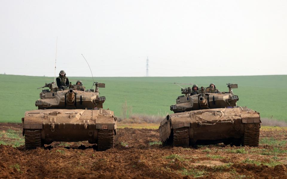 Israeli battle tanks roll at a position along the border with the Gaza Strip