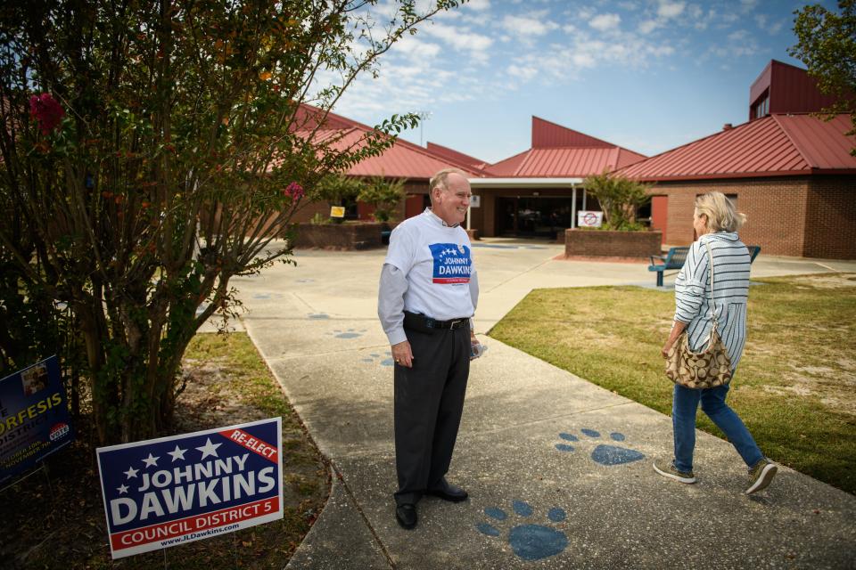 District 5 council member Johnny Dawkins engages with voters as they head into Max Abbott Middle School to vote on Tuesday, Oct. 10, 2023.