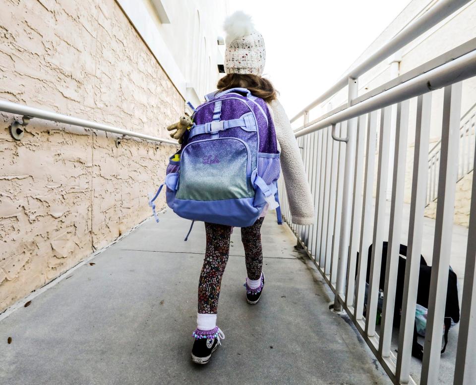 A girl dressed in warm clothing heads to class before the start of school at Palm Beach Public on Monday. The morning temperature dipped to the mid 40s.