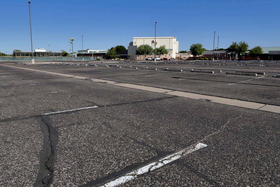 A parking lot is empty at a local high school Tuesday, June 30, 2020, in Tempe, Ariz. Schools will remain vacant two weeks longer this summer after Arizona Gov. Doug Ducey re-shut down bars, movie theaters, gyms, water parks and his delayed the start of school amid a dramatic resurgence of coronavirus cases. (AP Photo/Matt York)
