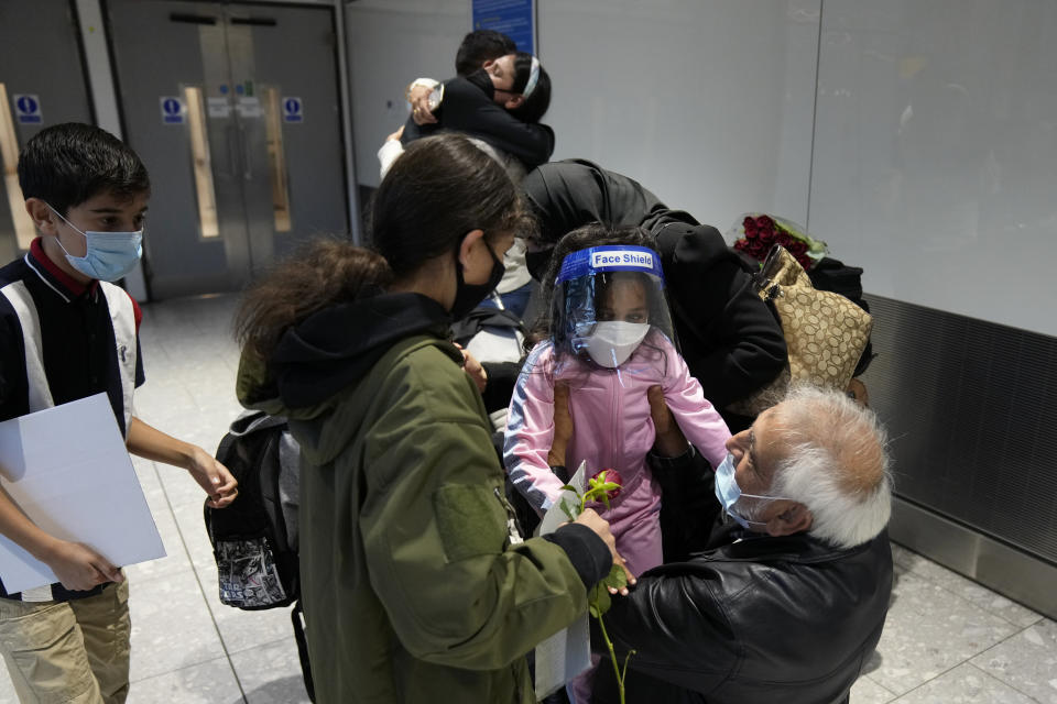 Members of the Mogul family are reunited as a grandfather embraces his granddaughter who arrived with her mother, top, on a flight from Charlotte, North Carolina, in the U.S. at Terminal 5 of Heathrow Airport in London, Monday, Aug. 2, 2021. Travelers fully vaccinated against coronavirus from the United States and much of Europe were able to enter Britain without quarantining starting today, a move welcomed by Britain's ailing travel industry. (AP Photo/Matt Dunham)