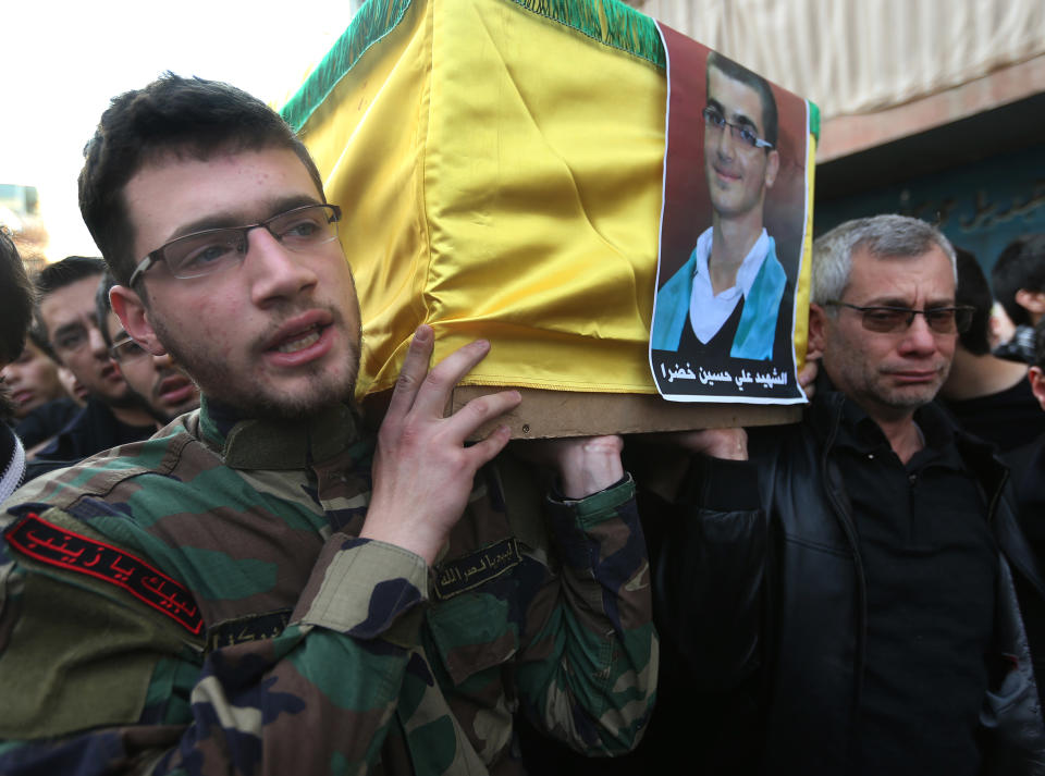 The father, right, and brother of Ali Khadra, left, who was killed Thursday by a bomb explosion, carry his coffin during his funeral procession in the southern suburb of Beirut, Lebanon, Saturday, Jan. 4, 2014. An explosion tore through a crowded commercial street Thursday in a south Beirut neighborhood that is bastion of support for the Shiite group Hezbollah, killing several people, setting cars ablaze and sending a column of black smoke above the Beirut skyline. (AP Photo/Hussein Malla)