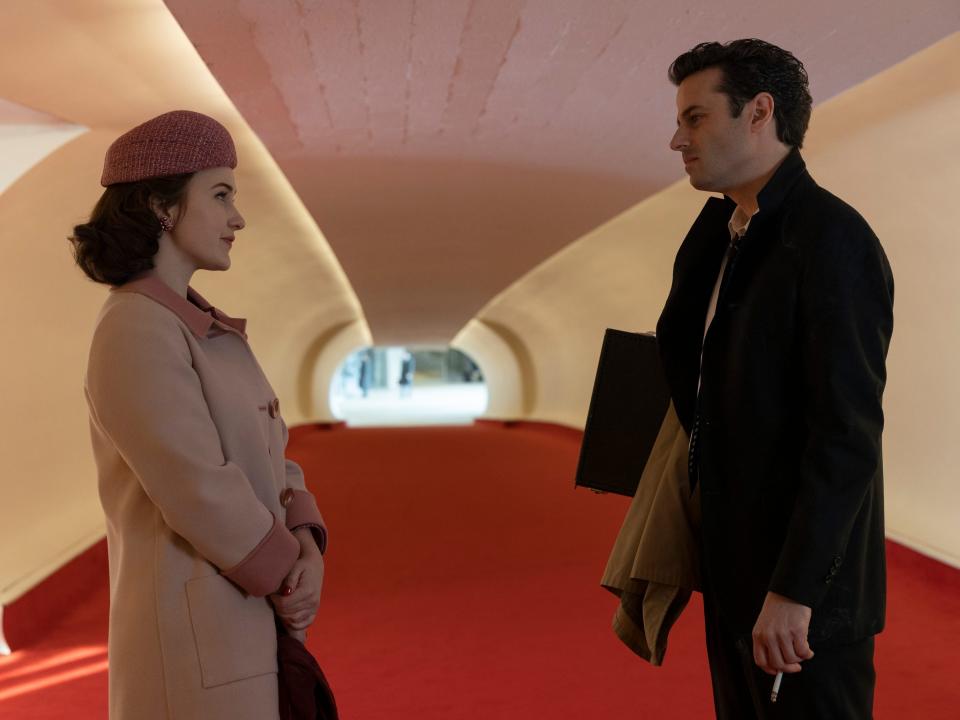 Rachel Brosnahan (Miriam 'Midge' Maisel) and Luke Kirby (Lenny Bruce) looking at each other in a hallway with a red carpet on "The Marvelous Mrs. Maisel."