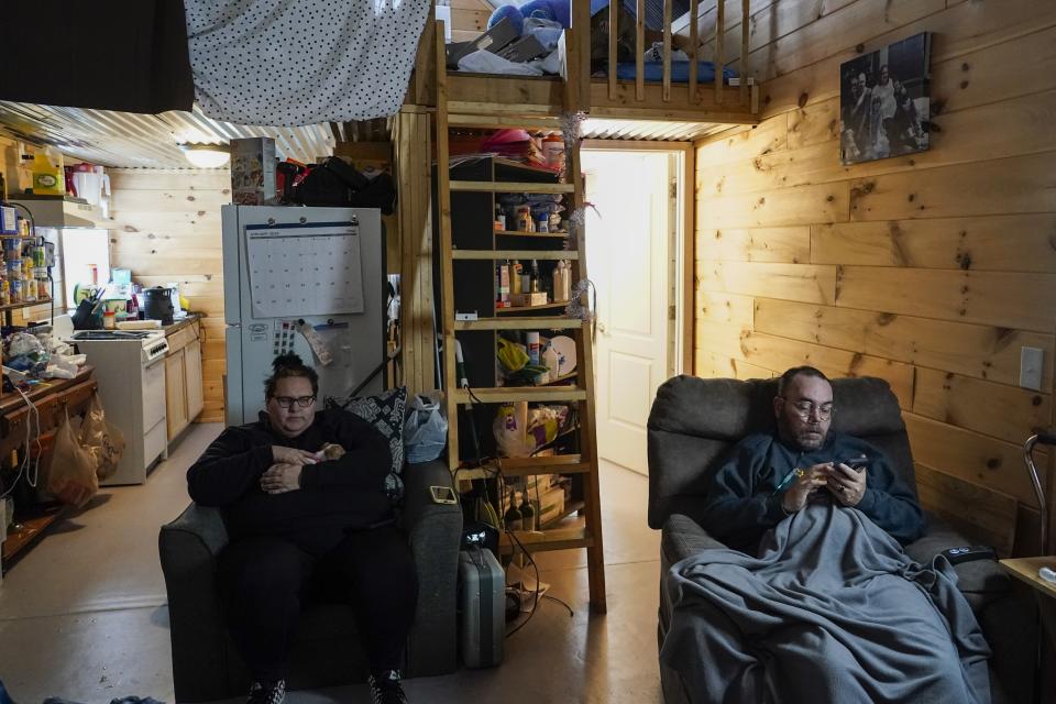 Cayla Callan, left, and her husband, James, right, sit inside their temporary home at Camp Graves, a nonprofit helping provide temporary housing, Wednesday, Jan. 17, 2024, in Water Valley, Ky. They moved into Camp Graves a year and two months after the tornado hit, after several months of living with family members. (AP Photo/Joshua A. Bickel)