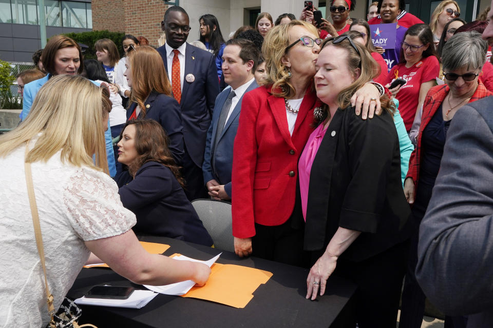 Former Rep. Gabby Giffords, center, hugs Michigan State Rep. Kelly Breen, Monday, May 22, 2023, in Royal Oak, Mich., after a package of legislation was signed to create extreme risk protection orders, which authorize family, police officers, or medical professionals to seek a court order to temporarily keep guns out of the hands of someone who represents a danger to themselves or others. (AP Photo/Carlos Osorio)