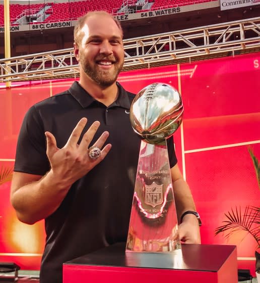 Mitchell Schwartz shows his championship ring as hje poses with the Vince Lombardi Trophy.