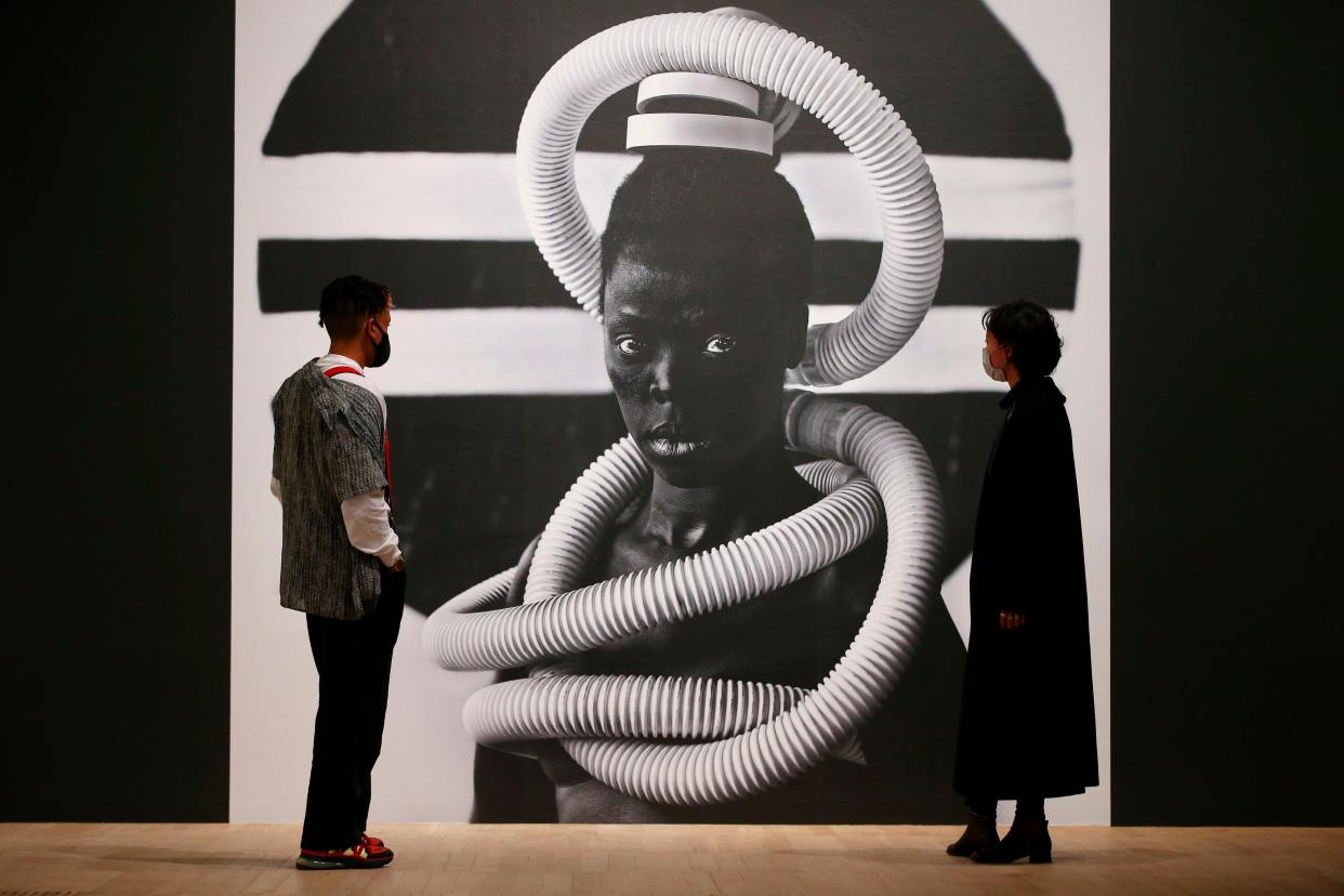 <p>Tate visitors pose in front of a self portrait photograph from an on-going series entitled 'Somnyama Ngonyama' by South African visual activist Zanele Muholi</p> (AFP via Getty Images)