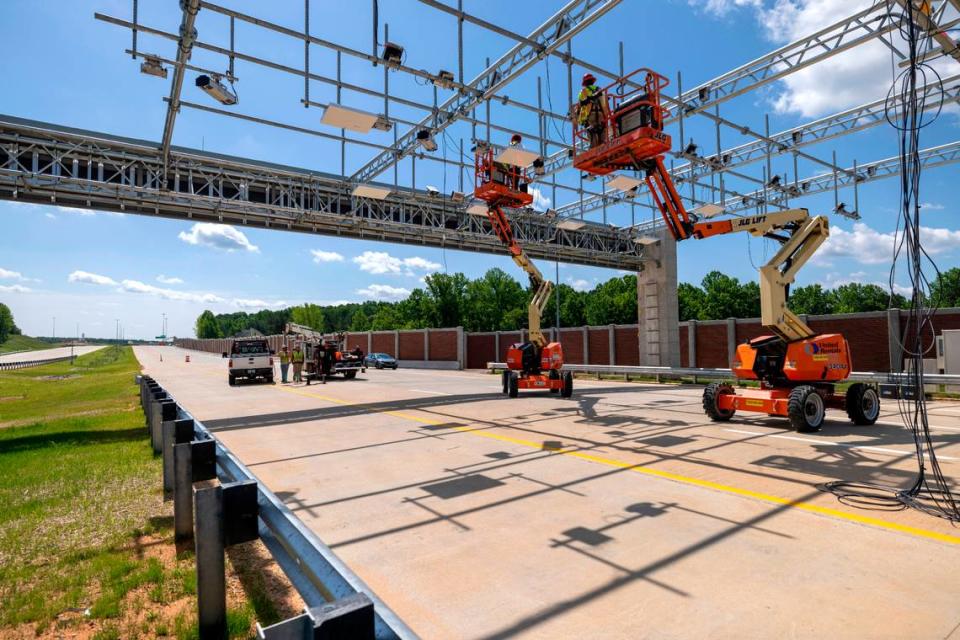 Workers install cameras and sensors on a gantry over the highway to collect tolls for the N.C. Turnpike Authority.