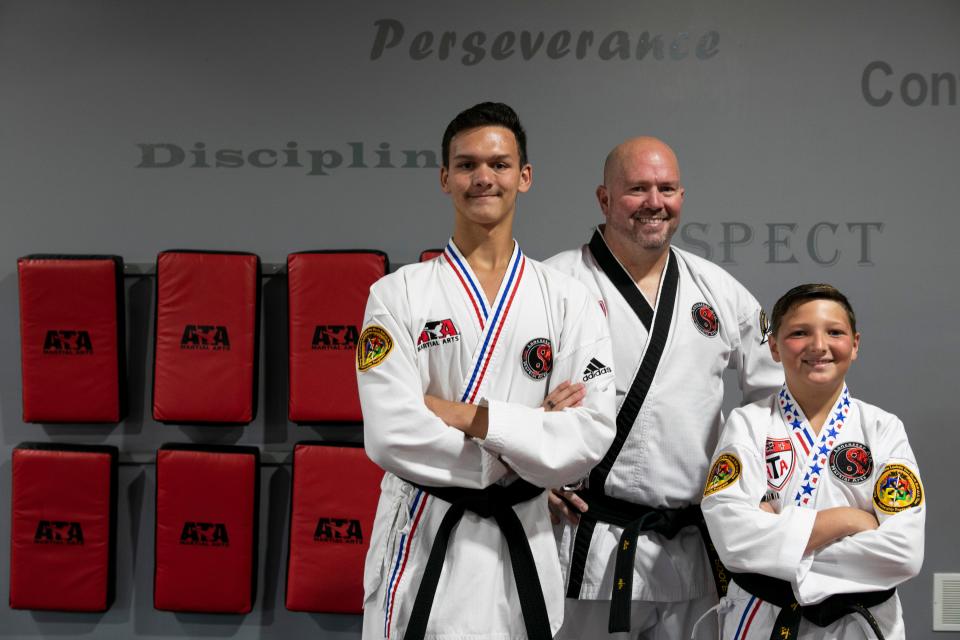 Fifth degree Black Belt and instructor owner Michael Poole (middle), Jaxon Lowry (right), 10 of Lancaster, and Liam Kinder, 16 of Carroll, stand together inside of the Lancaster ATA Martial Arts on July 31, 2023, in Lancaster, Ohio. The Taekwondo students, along with instructor Michael Poole, went to the ATA World Championships in Phoenix, Arizona where Kinder took third in traditional sparring, and Evelyn Hill (not shown), 16, took first place in extreme weapons. Lowry did not place in worlds but won first place in traditional sparring and combat at the state level championship.