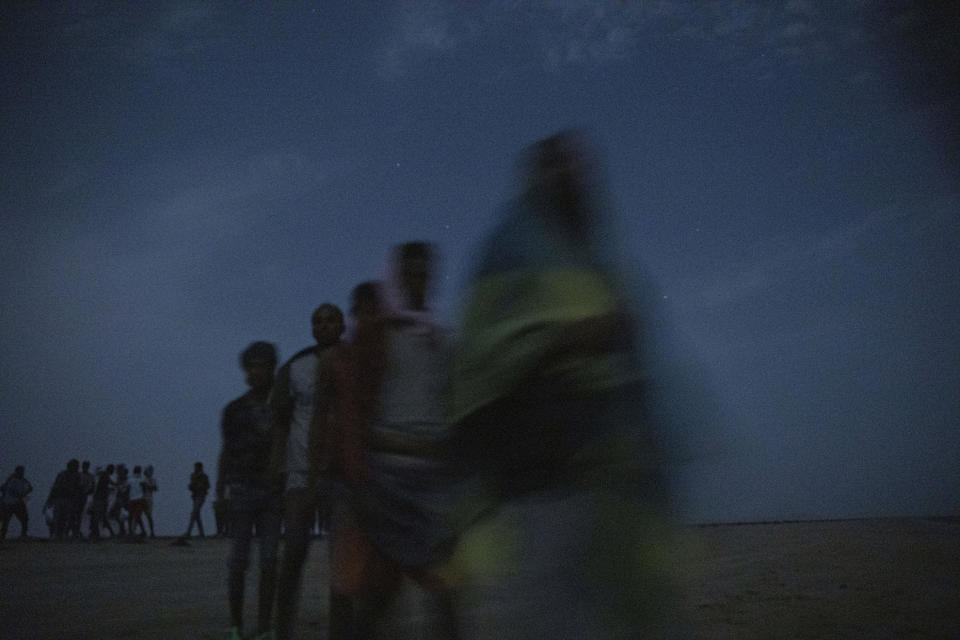 In this July 15, 2019 photo, Ethiopian migrants stand in line to board a boat on the uninhabited coast outside the town of Obock, Djibouti, the shore closest to Yemen. More than 100 Ethiopian men and women, boys and girls were ordered to sit in total silence. Only the smugglers spoke, in hushed conversations on satellite phones to their counterparts in Yemen on the other side of the sea. (AP Photo/Nariman El-Mofty)