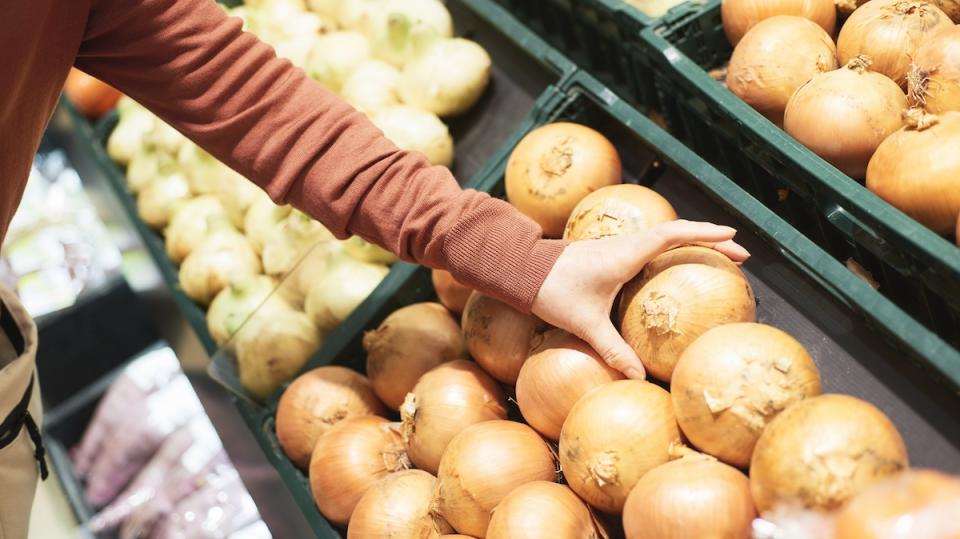 Woman reaches for onions at the grocery store