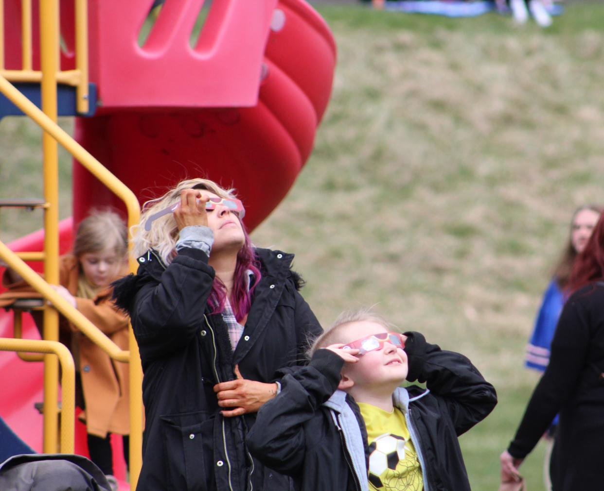 Eclipse gazers look skyward as the sun poked through the clouds, offering a glimpse of the partial solar eclipse during an event at Shawmut Park in Hornell Monday, April 8, 2024.