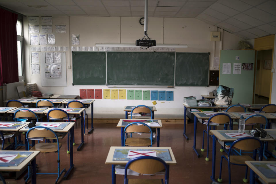 Desks marked with signs to enforce social distancing measures are pictured at the Saint-Tronc Castelroc primary school, which will begin to receive students on a voluntary basis, in Marseille, southern France, Monday, May 11, 2020. France is beginning to reopen Monday after two months of virus confinement measures. Shops, hair salons and some other businesses are reopening Monday and French citizens no longer need a special permission form to leave the house. (AP Photo/Daniel Cole)