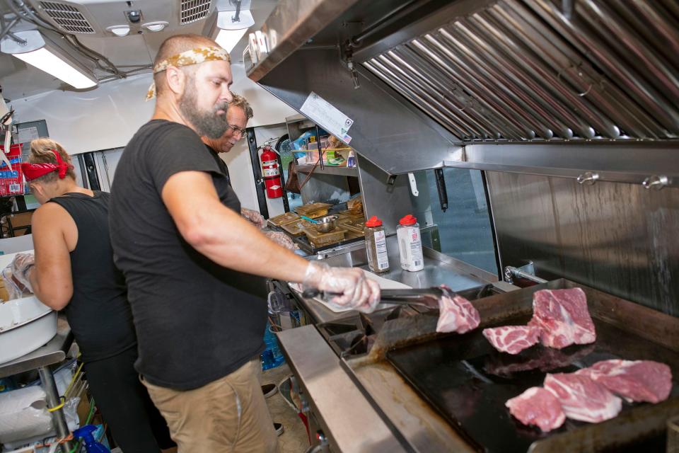 Kyle and Katherine Staples, along with Frank Humphreys, prepare food Tuesday at their P'Cola Rolla food truck.