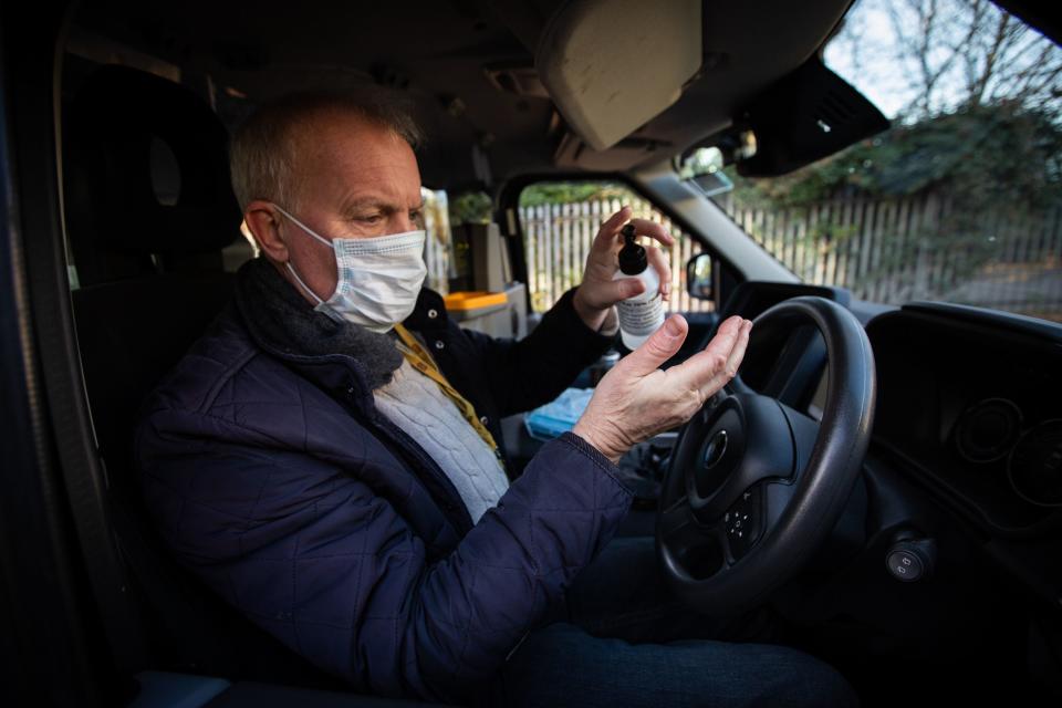 <p>London taxi driver using hand sanitiser after dropping off a customer</p> (PA)