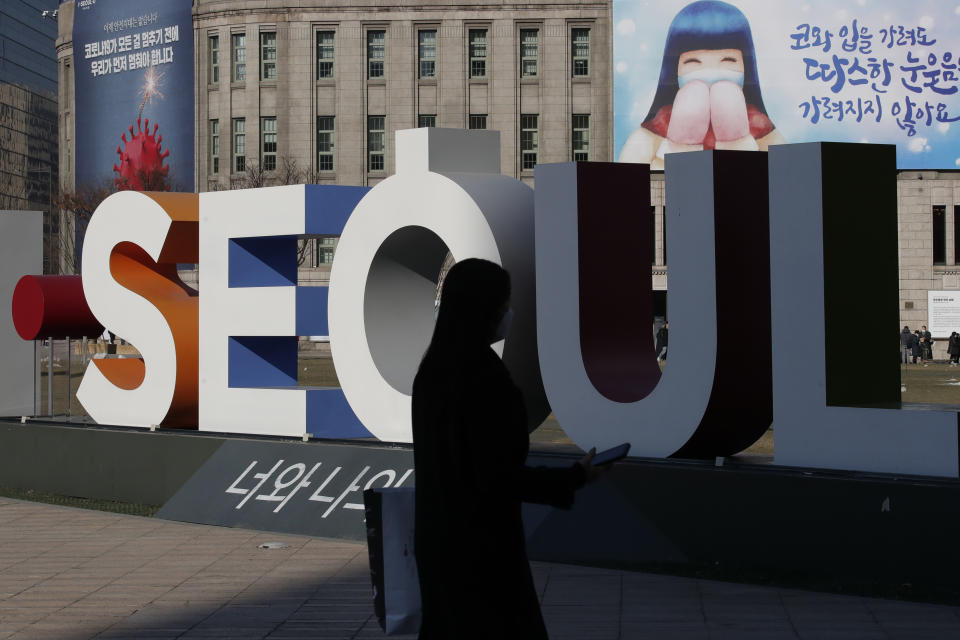 A woman wearing a face mask as a precaution against the coronavirus walks near the display of South Korea's capital Seoul logo in Seoul, South Korea on Dec. 21, 2020. South Korea had seemed to be winning the fight against the coronavirus: Quickly ramping up its testing, contact-tracing and quarantine efforts paid off when it weathered an early outbreak without the economic pain of a lockdown. But a deadly resurgence has reached new heights during Christmas week, prompting soul-searching on how the nation sleepwalked into a crisis. (AP Photo/Lee Jin-man)