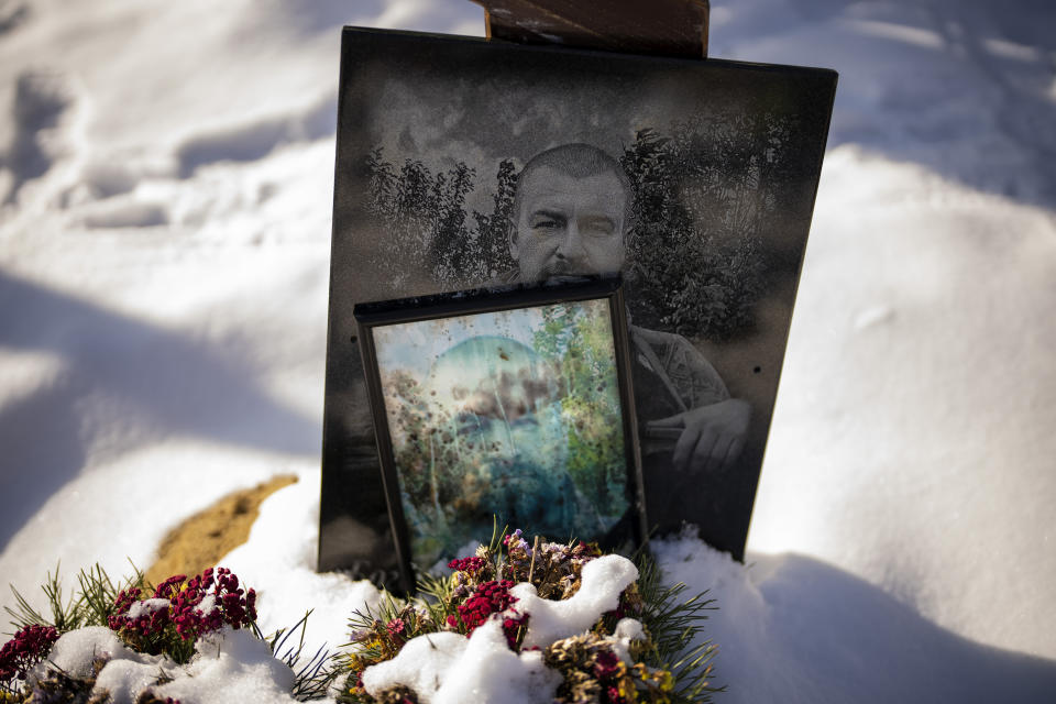 Portraits of soldier Bogdan Volodymrovych, 46, sit on his grave at a cemetery in Irpin, Ukraine, on the outskirts of Kyiv, on Thursday, Feb. 9, 2023. He was killed on May 31, 2022. (AP Photo/Emilio Morenatti)