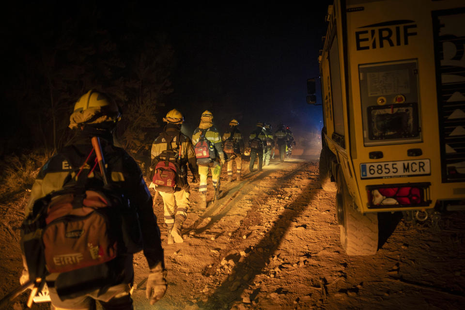 Emergency crews and firefighters walk to the fire advancing through the forest near the town of El Rosario in Tenerife, Canary Islands, Spain on Friday, Aug. 18, 2023. Officials say a wildfire is burning out of control through the Spanish Canary Island of Tenerife, affecting nearly 8,000 people who have been evacuated or ordered to stay indoors. (AP Photo/Arturo Rodriguez)