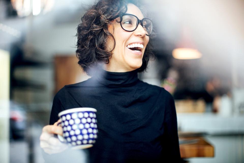 person holding coffee cup laughing