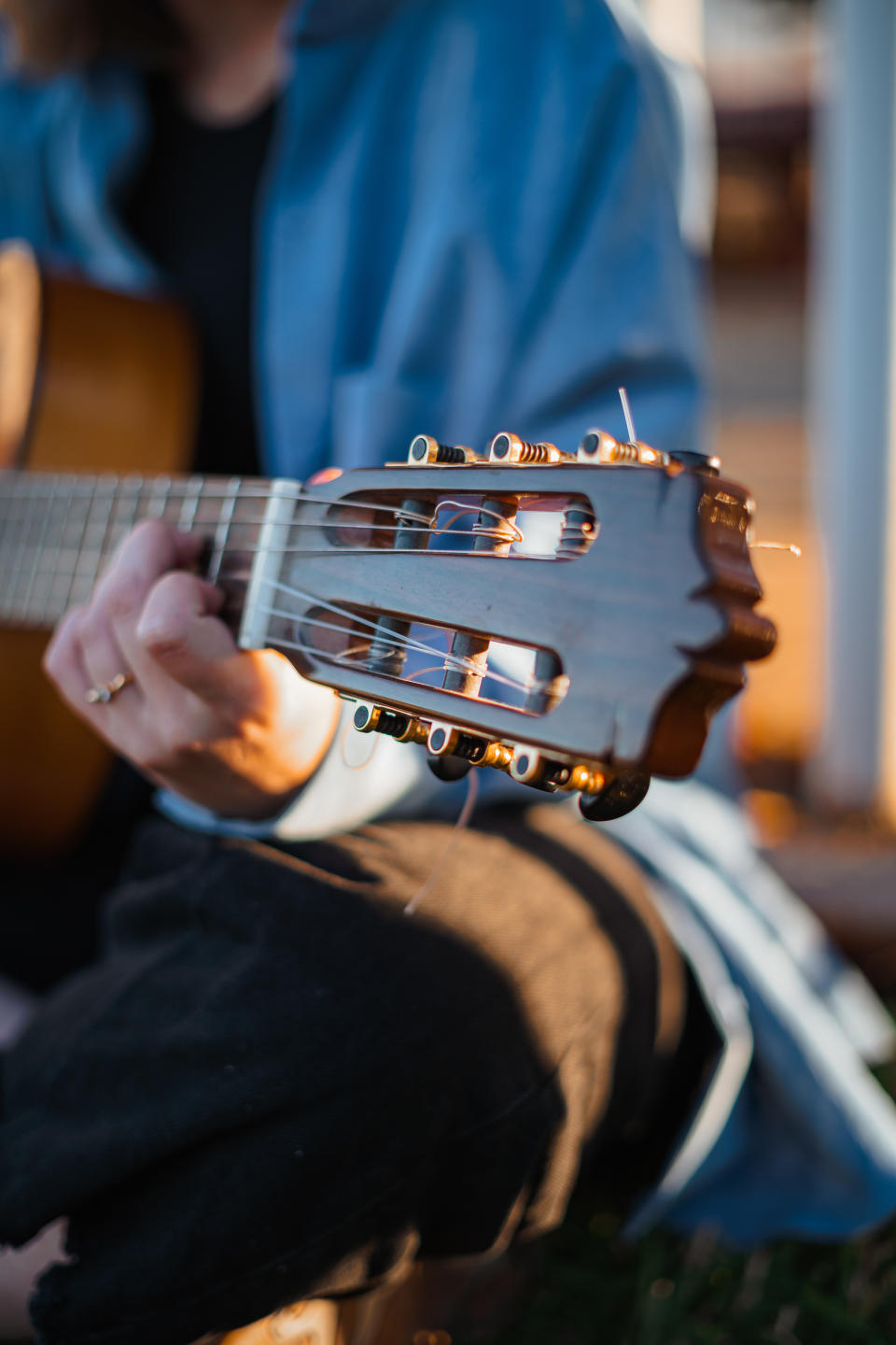 Close-up of a person's hands tuning an acoustic guitar