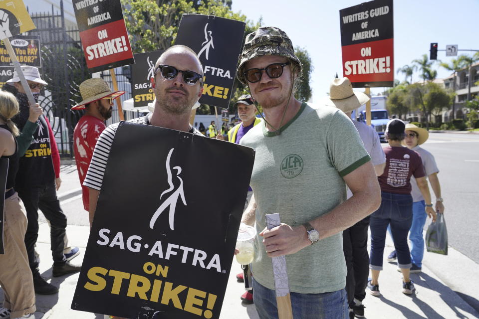Aaron Paul, left, and Jesse Plemons, pose on a picket line outside Sony Pictures studios on Tuesday, Aug. 29, 2023, in Culver City, Calif. The film and television industries remain paralyzed by Hollywood's dual actors and screenwriters strikes. (AP Photo/Chris Pizzello)