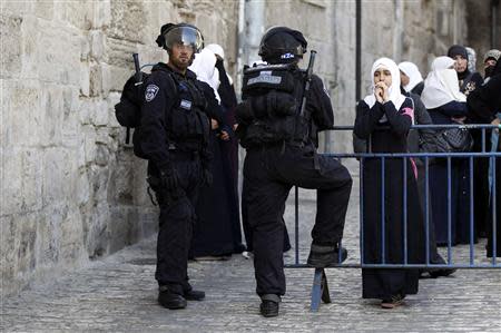 A Palestinian woman looks on as Israeli policemen prevent people from entering the compound which houses al-Aqsa mosque and is known to Muslims as Noble Sanctuary and to Jews as Temple Mount, in Jerusalem's Old City April 16, 2014. REUTERS/Ammar Awad