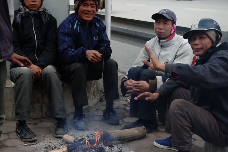 Migrant job seekers sit around a fire to keep warm on a street in Hanoi, on February 6, 2013. From growing numbers of people with depression to families bankrupted by stock market investments, many are suffering in Vietnam's slow-burn economic crisis -- and blame the communist regime for their woes