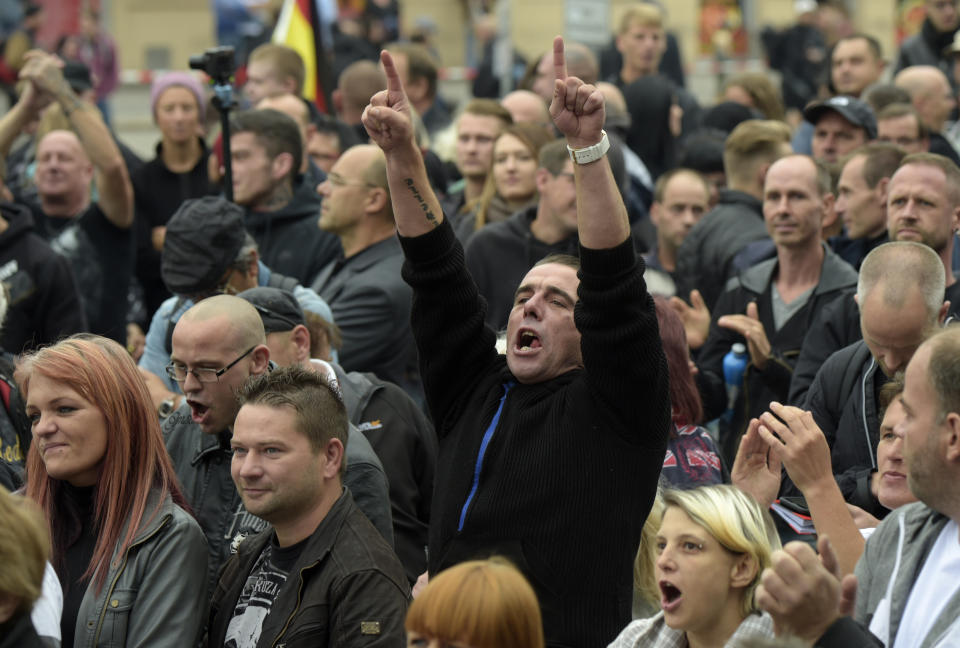 A demonstrator raises his arms in Chemnitz, eastern Germany, Saturday, Sept. 1, 2018, after several nationalist groups called for marches protesting the killing of a German man last week, allegedly by migrants from Syria and Iraq. (AP Photo/Jens Meyer)