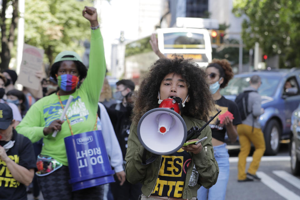 Protesters chant as they march near City Hall, Monday, July 13, 2020, following a news conference held by Seattle Mayor Jenny Durkan, Police Chief Carmen Best, and Fire Chief Harold Scoggins. Durkan and Best were critical of a plan backed by several city council members that seeks to cut the police department's budget by 50 percent. (AP Photo/Ted S. Warren)