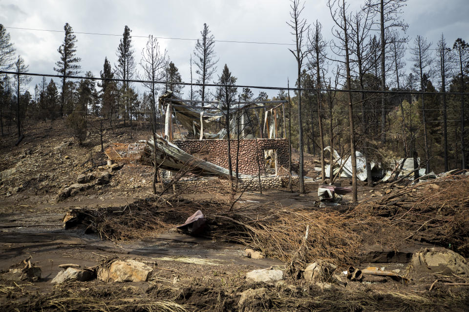 The remains of a house destroyed by the South Fork Fire are pictured among the effects of flash floods in the mountain village of Ruidoso, N.M., Saturday, June 22, 2024. (AP Photo/Andres Leighton)