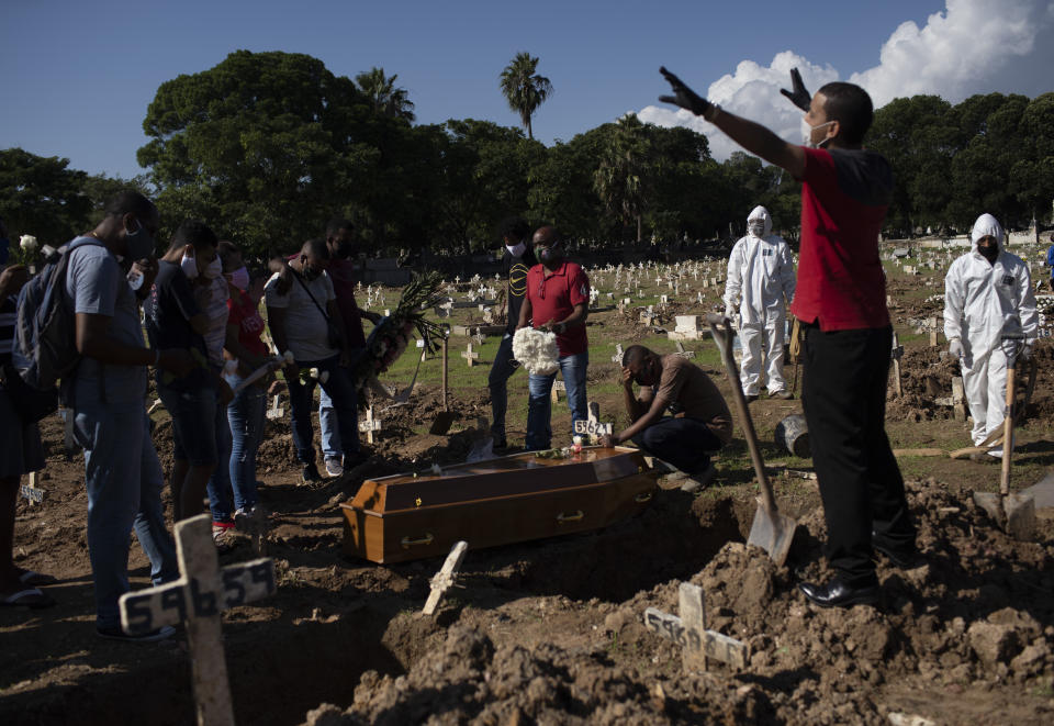 Relatives pray during the burial of Amanda da Silva, who died of COVID-19 at the Caju Cemetery, in Rio de Janeiro, Brazil, Wednesday, May 20, 2020. (AP Photo/Silvia Izquierdo)