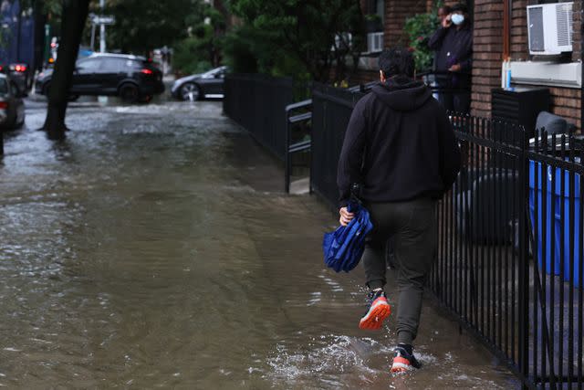 <p>Michael M. Santiago/Getty</p> A person walking on Caton Avenue in N.Y.C. during the flood on Sept. 29, 2023.