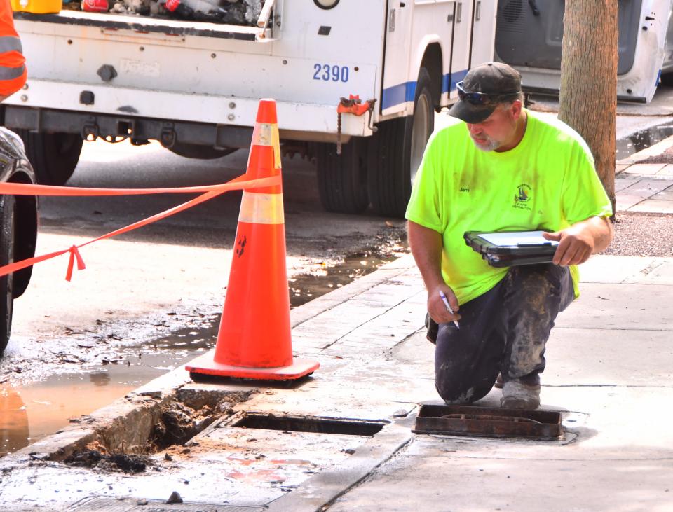 Jerry Baum, a maintenance worker with Melbourne's water distribution department, examines a leaking water line beneath the New Haven Avenue sidewalk Tuesday in downtown Melbourne.