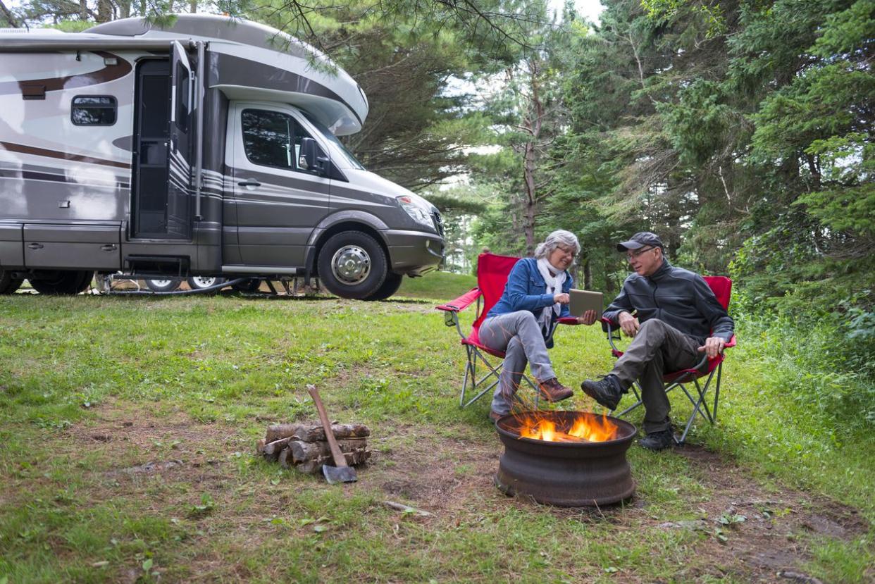 Couple looking at digital tablet near campfire