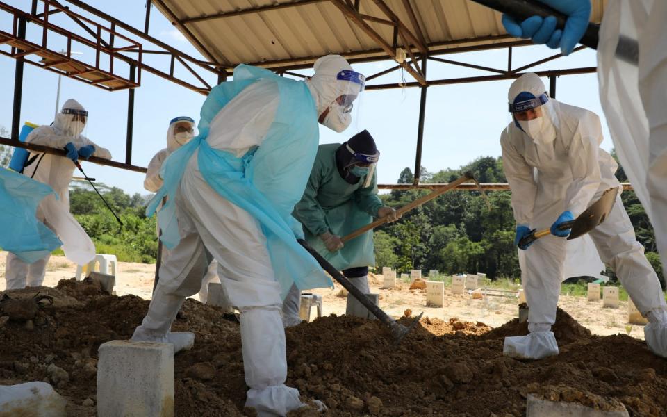 Malaysian Muslim cleric Rafie Zainal and his team members assist family members of a coronavirus disease (COVID-19) victim during a burial at a cemetery, in Gombak - Reuters