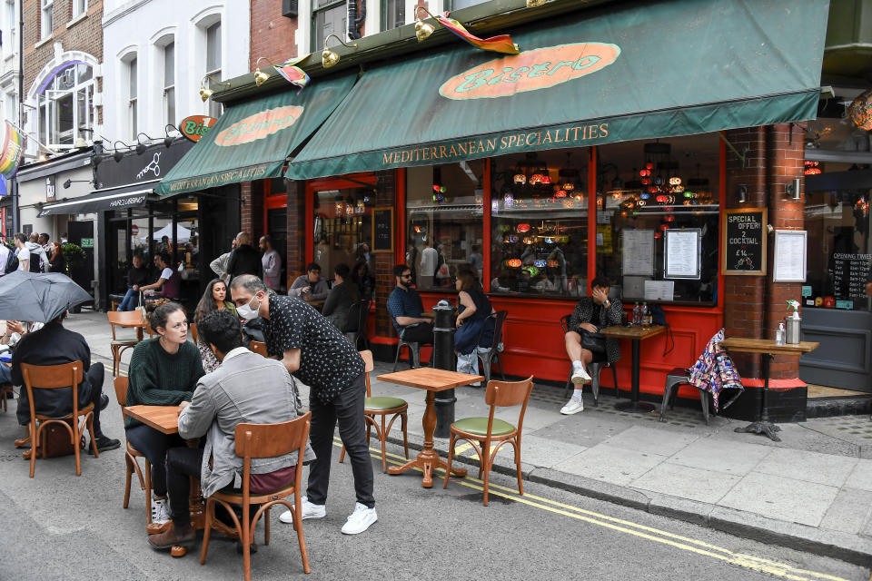 People sit and drink, outside a restaurant in Soho, as the capital is set to reopen after the lockdown due to the Coronavirus outbreak, in London, Saturday, July 4, 2020. England is embarking on perhaps its biggest lockdown easing yet as pubs and restaurants have the right to reopen for the first time in more than three months. In addition to the reopening of much of the hospitality sector, couples can tie the knot once again, while many of those who have had enough of their lockdown hair can finally get a trim. (AP Photo/Alberto Pezzali)