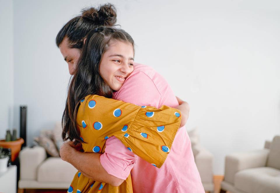 A parent and child embracing indoors while smiling, expressing affection and joy