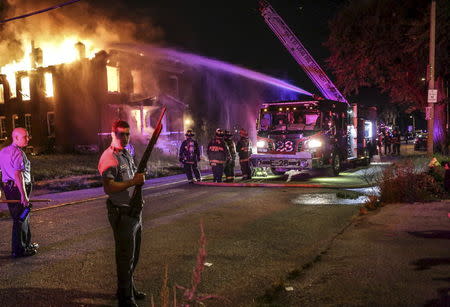 Firefighters attempt to put out a fire at an abandoned building with the protection of St. Louis City Police in St. Louis, Missouri August 19, 2015. REUTERS/Lawrence Bryant