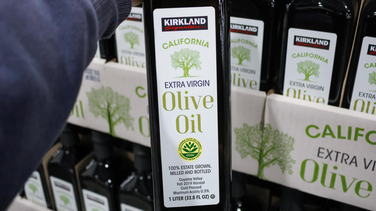 Alhambra, California/United States - 02/19/2020: A hand holds a bottle of Kirkland Signature California Extra Virgin Olive Oil, on display at a local Costco.