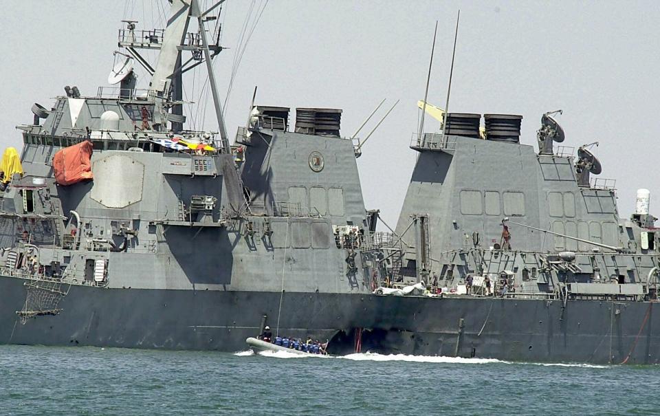 FILE - In this Oct. 15, 2000 file photo, experts in a speed boat examine the damaged hull of the USS Cole at the Yemeni port of Aden after an al-Qaida attack that killed 17 sailors. Years after the death of his father at the hands of a U.S. Navy SEAL raid in Pakistan, Hamza bin Laden himself clearly in the crosshairs of world powers. The U.S. has put up to a $1 million bounty for him. The U.N. Security Council has named him to a global sanctions list, sparking a new Interpol notice for his arrest. His home country of Saudi Arabia has revoked his citizenship. (AP Photo/Dimitri Messinis, File)