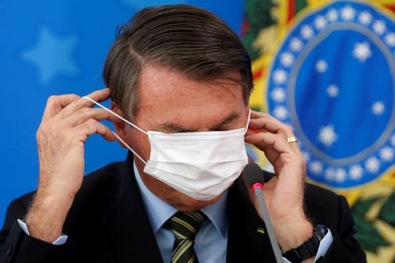 Brazil's Jair Bolsonaro adjusts his protective face mask during a news conference to announce measures to curb the spread of the coronavirus disease (COVID-19) in Brasilia