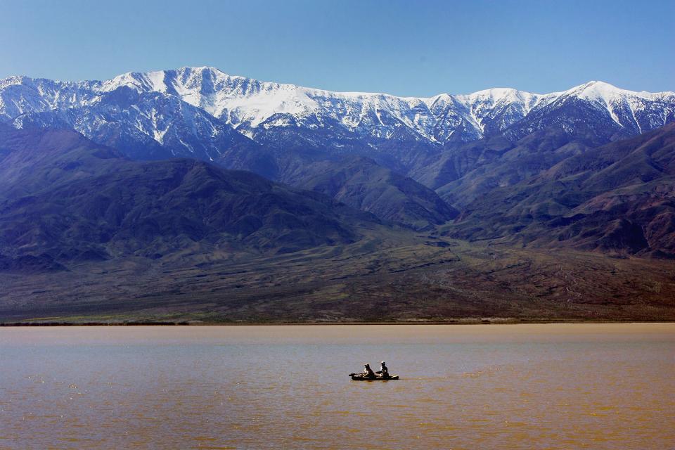 A couple kayaks on a giant lake in the bottom of Death Valley caused by heavy flooding in 2005. Pictured in the background are the snow-capped Panamint Mountains.