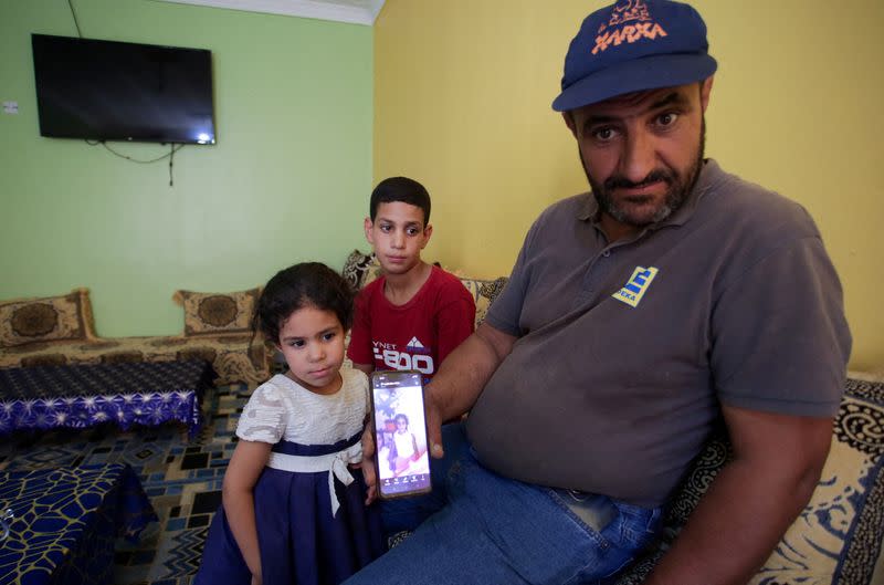 Amar, father of Algerian boxer Imane Khelif, sits with his children as he shows a picture of Imane when she was young, inside his house